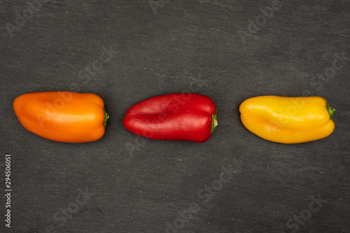 Group of three whole fresh pepper in row flatlay on grey stone photo