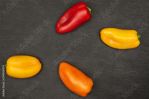 Group of four whole fresh pepper flatlay on grey stone