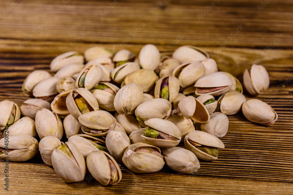 Pile of pistachio nuts on a wooden table Pile of pistachio nuts on a wooden table