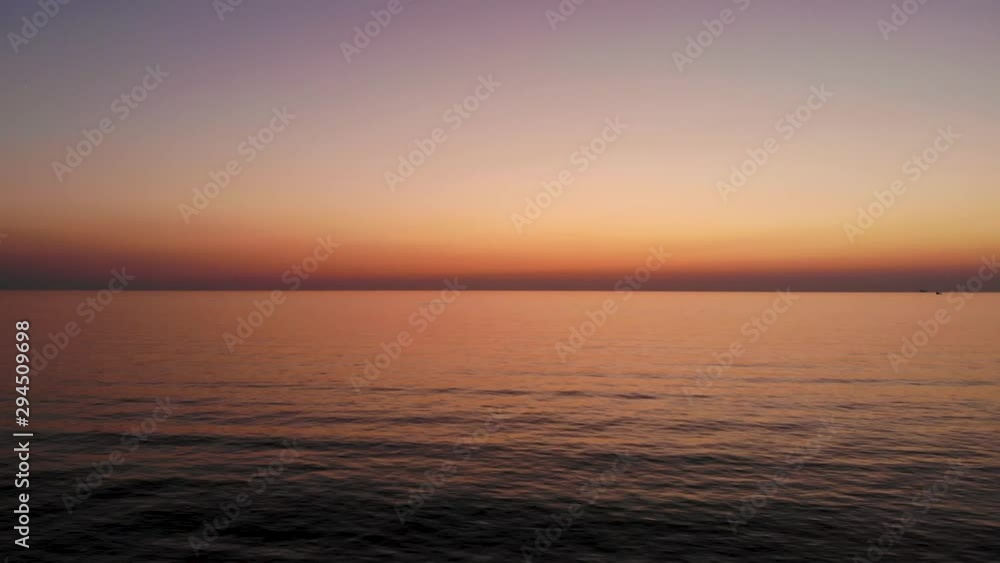 Flight over water to left parallel to sun that just set. Waves barely wave, shine from setting sun is still visible on horizon. Taken by drone at sunset Flight over water to left parallel to sun that just set. Waves barely wave, shine from setting sun is still visible on horizon. Taken by drone at sunset