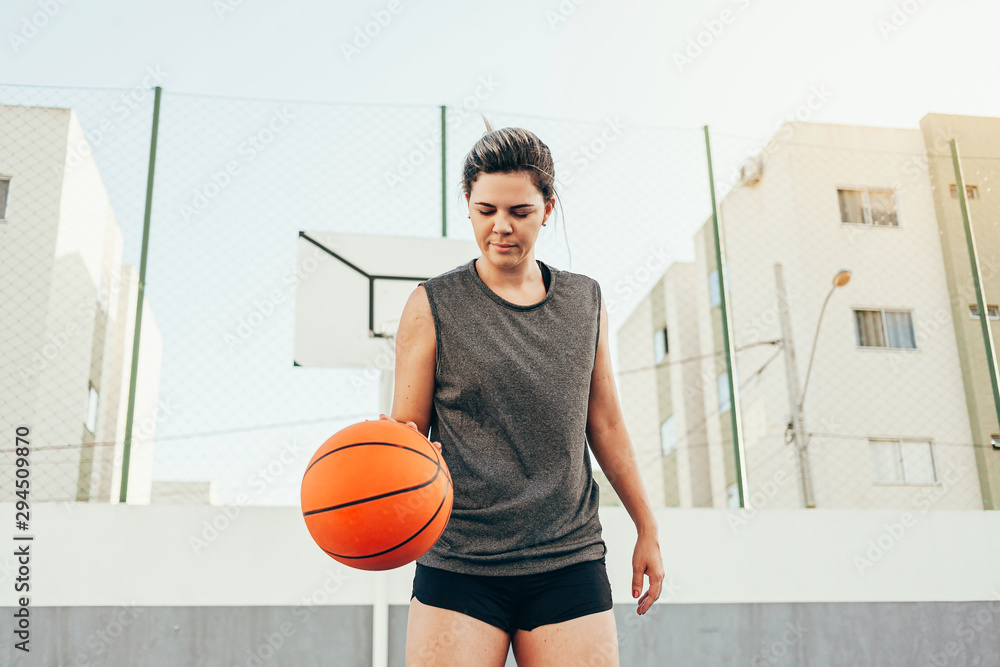 Young female basketball player training outdoors on a local court