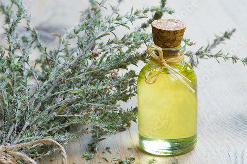 glass bottle of thyme essential oil and bunch of dry thyme on wooden rustic background. Dried spice zahter thyme and oil concept