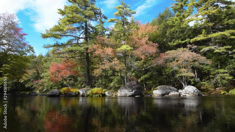 River flows through the Kejimkujik National Park in Nova Scotia, Canada. Autumn leaves on the trees. River flows through the Kejimkujik National Park in Nova Scotia, Canada. Autumn leaves on the trees.