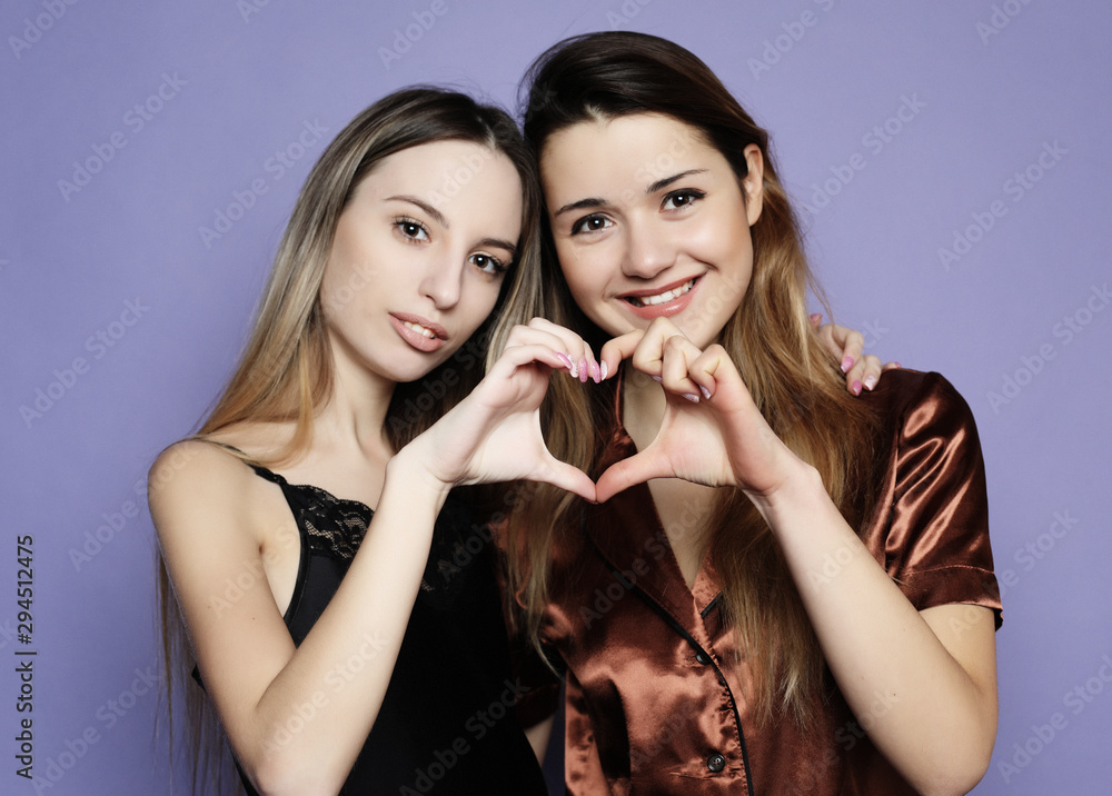 lifestyle and people concept: two beautiful girls dressed in pajamas hugging and taking selfies lifestyle and people concept: two beautiful girls dressed in pajamas hugging and taking selfies