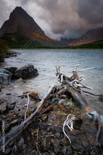 The wind moving the water at Swiftcurrent Lake, with the sunrise lighting up the mountains in the background, Montana.