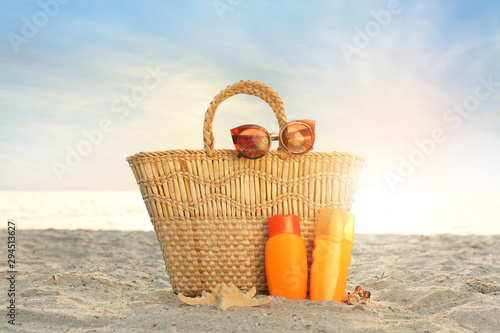 Beach bag, sunglasses and sunscreen cream on sea shore