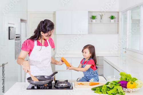 Little girl helping her mother cook in the kitchen