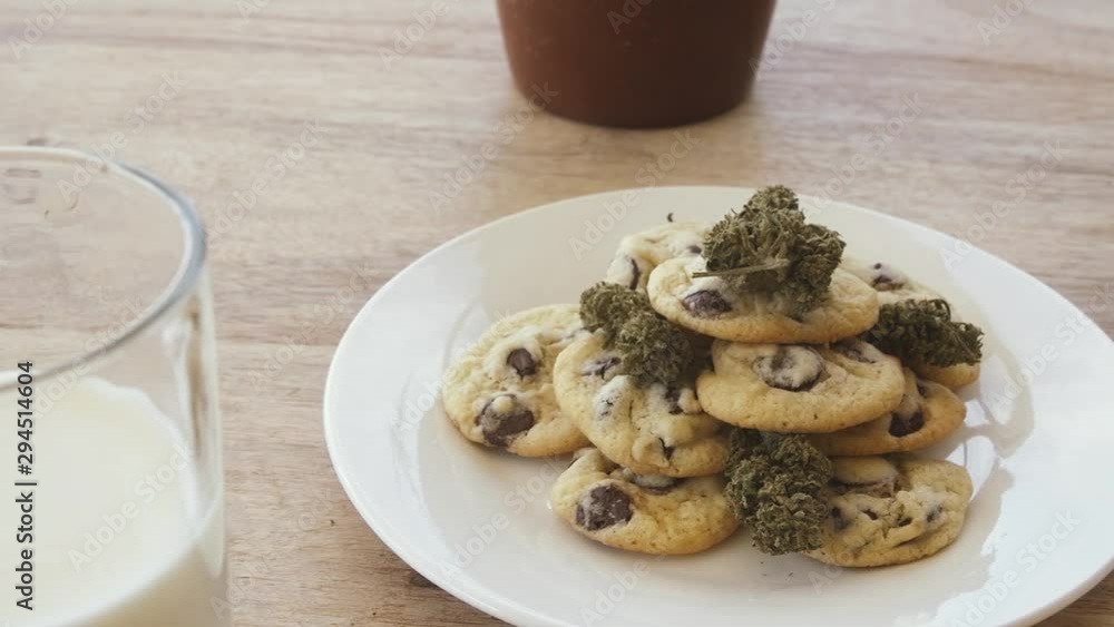 Track and focus shift from glass of milk to plate of chocolate chip space cookies on a white plate Track and focus shift from glass of milk to plate of chocolate chip space cookies on a white plate