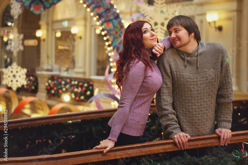 Loving couple meets Christmas. They spend time at the mall in holiday decorations. Lovers dressed in cozy knitted sweaters