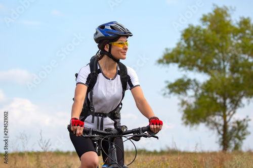 Beautiful girl cyclist rides on the field on a bicycle. Healthy lifestyle and sport