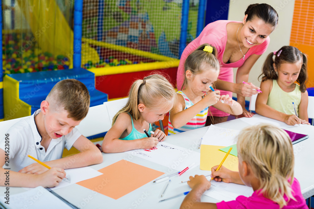Fototapeta premium Kids drawing together with tutor at hobby group