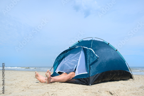 Man camping in shelter at the beach © Ivonne Wierink