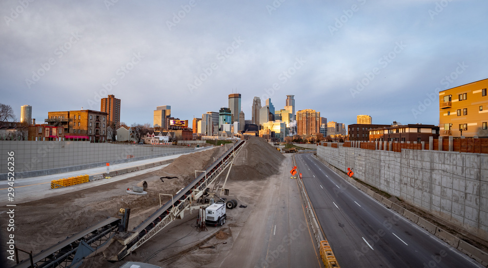 Downtown Minneapolis seen from freeway with construction and signs at dusk, sunset