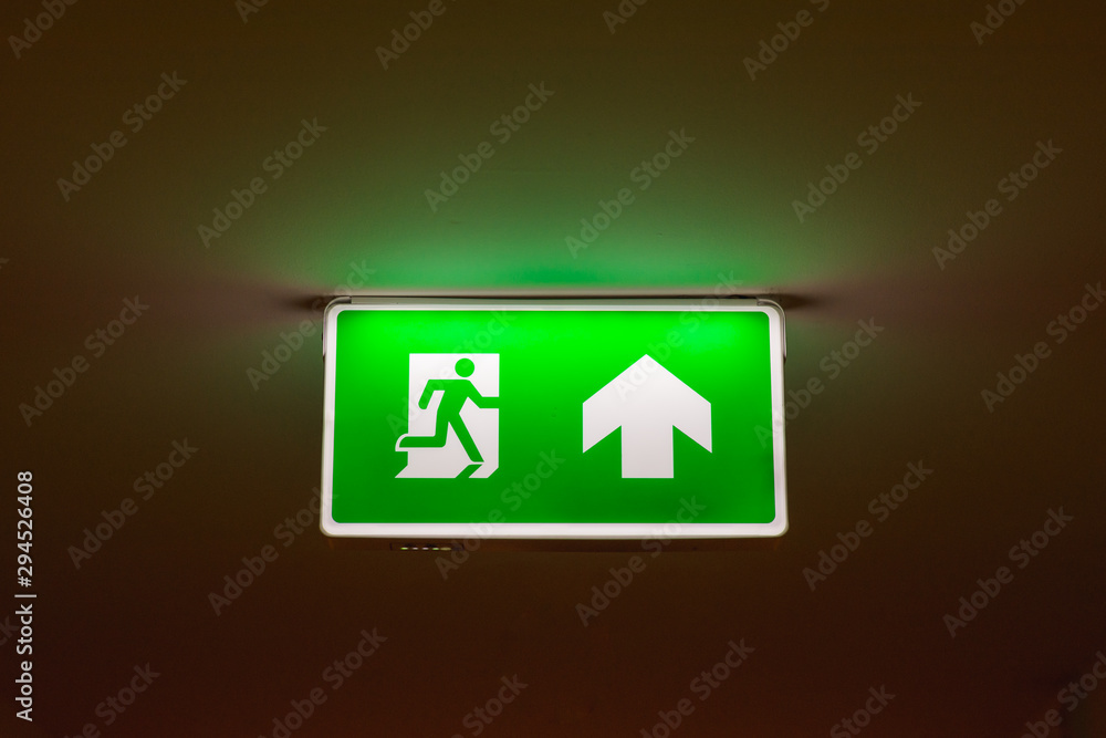 Emergency exit sign with arrow up in the hotel aisle. Safety first concept. Copy space wallpaper. Emergency exit sign with arrow up in the hotel aisle. Safety first concept. Copy space wallpaper.