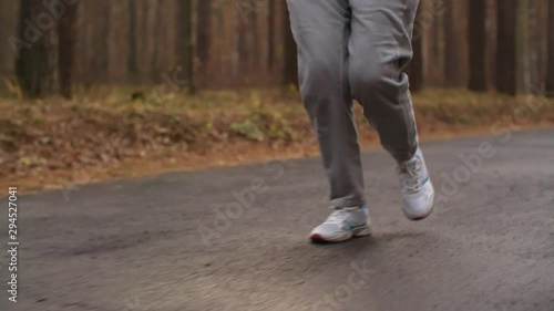 Wallpaper Mural Tilt up of old Caucasian woman in warm sportswear jogging alone in woods Torontodigital.ca