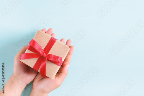 Fototapeta Naklejka Na Ścianę i Meble -  Hands holding gift box with red ribbon for giving