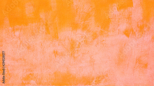 Wall painted with wide strokes in orange and pink paint. Bright saturated expressive joyful texture background