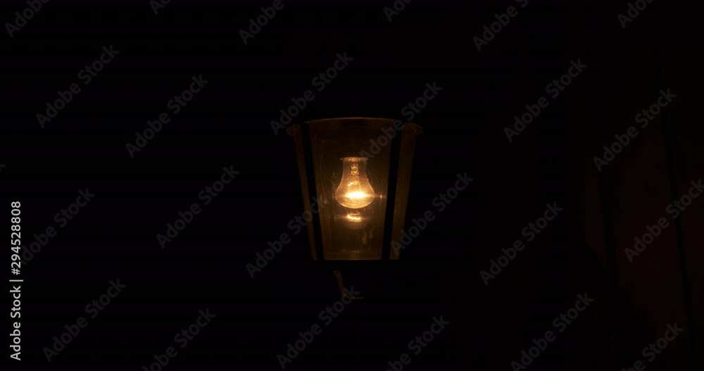 In pitch darkness of village night, small lamp shines in old iron lantern, lamp shines with warm light, lantern sways in wind, around there is complete darkness, an oppressive atmosphere In pitch darkness of village night, small lamp shines in old iron lantern, lamp shines with warm light, lantern sways in wind, around there is complete darkness, an oppressive atmosphere