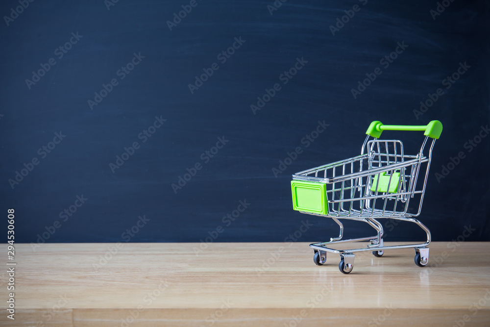 Shopping cart on wood table with black board backdrop. E-commerce and global network online business. copy space for art work design or add text message. Online shopping concept. 