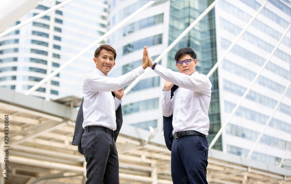 Two Businessmen Giving High Five While Standing In City Two Businessmen Giving High Five While Standing In City