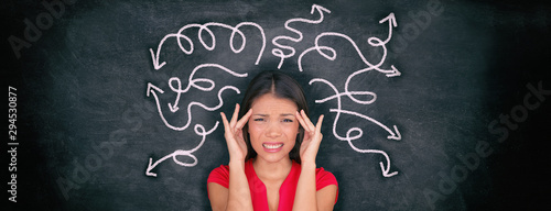 Confused woman confusion illustrated on blackboard with chalk drawing of arrows going everywhere around head showing indecision. Indecisive stressed Asian girl with headache panoramic banner.