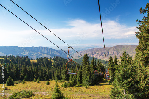 Summer mountain landscape high in the mountains. Tall trees of Christmas trees, ski lift at the ski base.