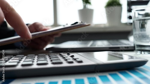 Silver calculator with gray keyboard is lying on desk graph and pen office setting. Calculation of family expenses social income population freelance irs situation growth research concept