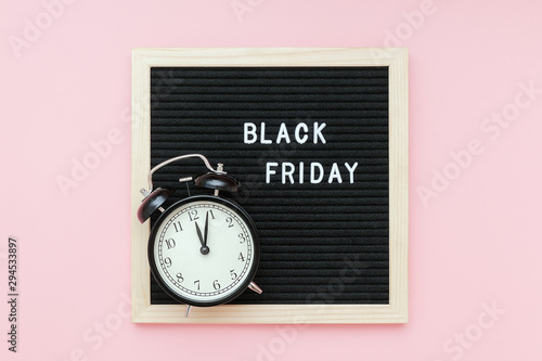 Text Black friday on black letter board and alarm clock on pink background. Concept Black friday , season sales time. Flat lay Top view Copy space Template layout for your design photo