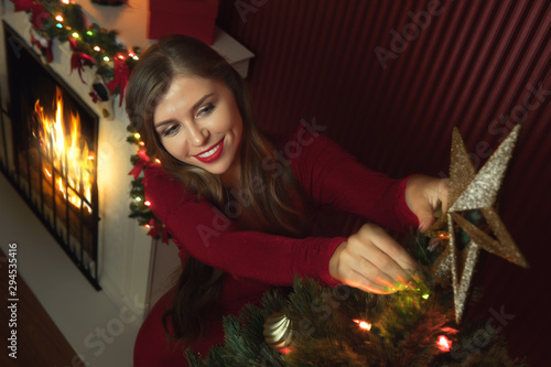 portrait of nice woman in red dress decorating christmas tree photo