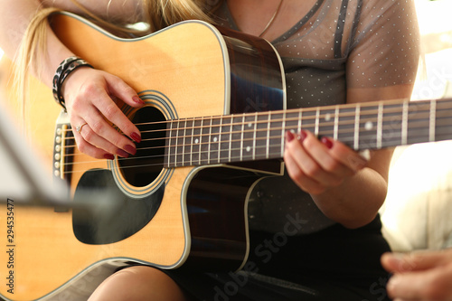Female hands holding and playing western acoustic guitar closeup process