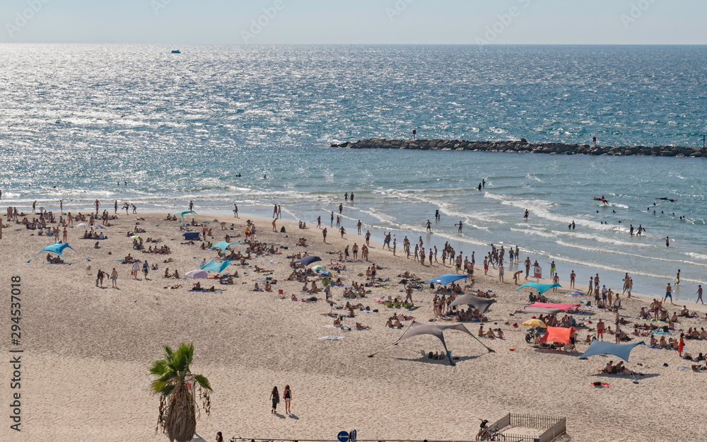swimmers and sunbathers enjoying a mediterranean beach in Tel Aviv Israel with a clean sandy beach in the foreground and the sea beyond the breakwater in the background swimmers and sunbathers enjoying a mediterranean beach in Tel Aviv Israel with a clean sandy beach in the foreground and the sea beyond the breakwater in the background