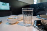 Glass of water sitting in resturant with various bowls and hot pot