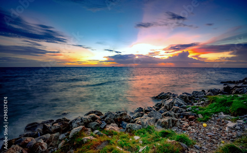 Rocks on stone beach at sunset. Beautiful beach sunset sky. Twilight sea and sky. Tropical sea at dusk. Dramatic sky and clouds. Calm and relax life. Nature landscape. Tranquil and peaceful concept.