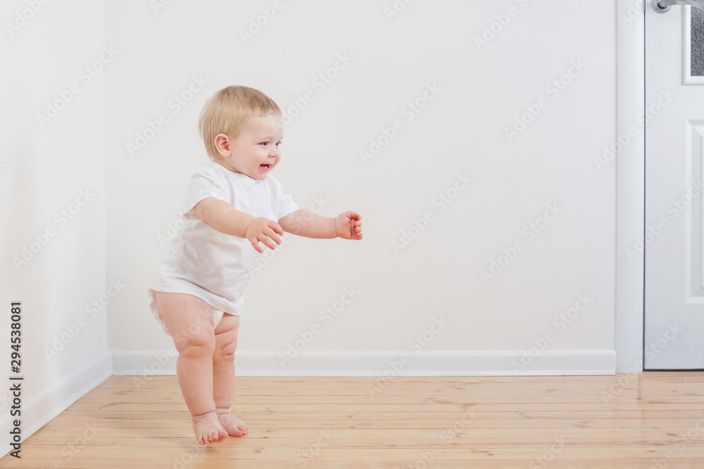 funny little  baby takes first steps on wooden floor