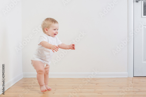 funny little  baby takes first steps on wooden floor