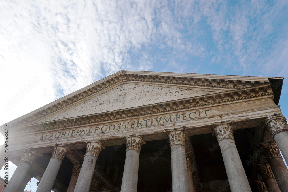 View to the portico of the Pantheon with columns upwards against blue sky with clouds in the Rome city in Italy