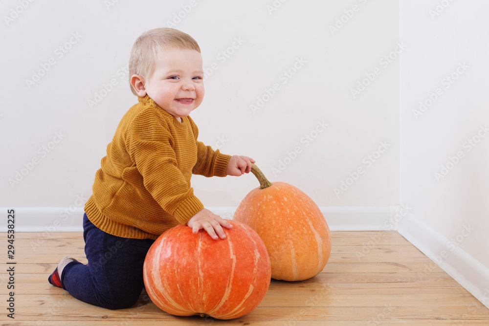 Fototapeta premium little boy with pumpkins on wooden floor
