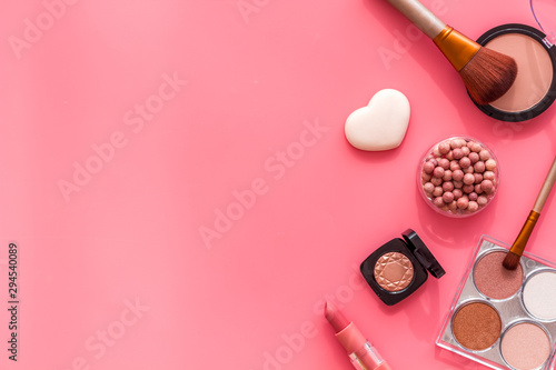 Makeup concept. Frame with decorative cosmetics and brushes on pink background top view copy space