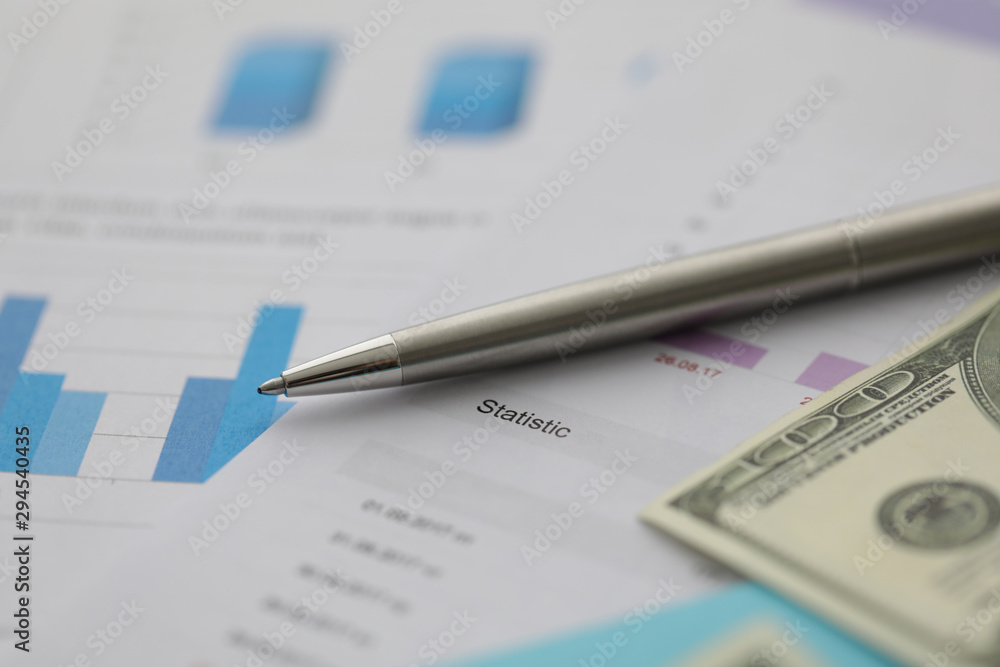 Silver ballpen lie on dollar cash with business chart info graph background. Business education seminar concept Silver ballpen lie on dollar cash with business chart info graph background. Business education seminar concept