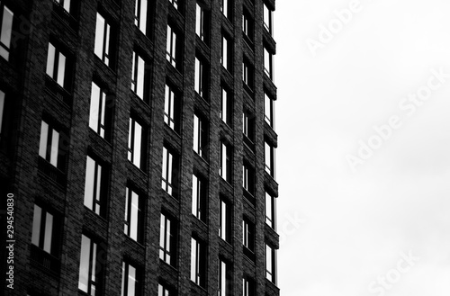 Tall building with windows in black and white with white cloudy sky background photo