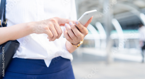 close up businesswoman hand holding smartphone to answer customer and vendor or checking email from company at outdoor city town in the morning for business concept