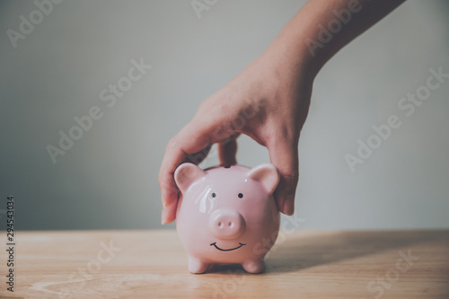 Man hand holding piggy bank on wood table. Save money and financial investment