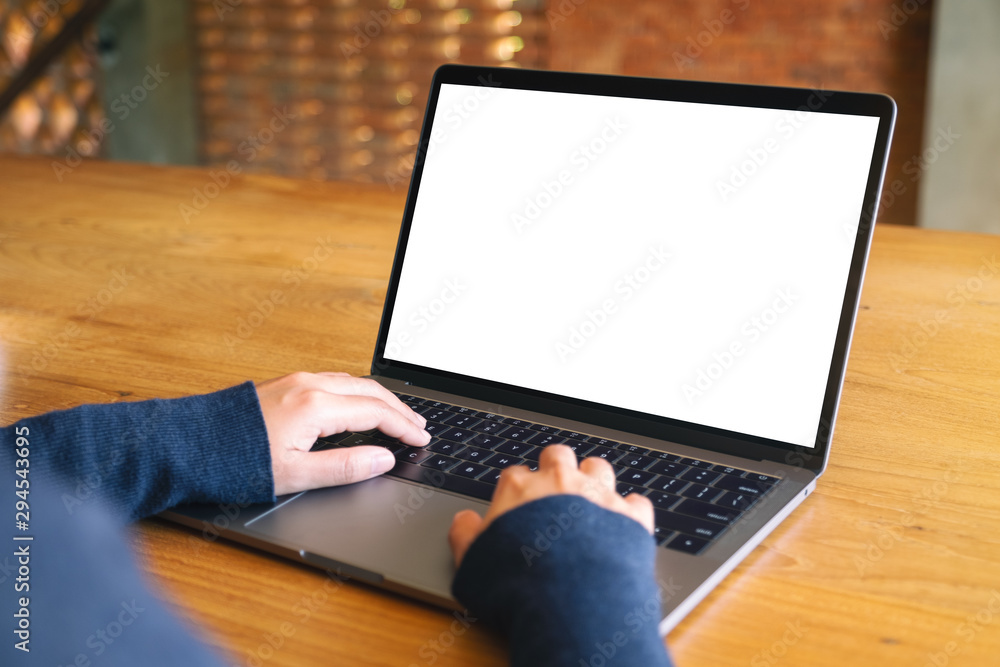 Mockup image of a woman using and typing on laptop computer keyboard with blank white desktop screen on wooden table Mockup image of a woman using and typing on laptop computer keyboard with blank white desktop screen on wooden table