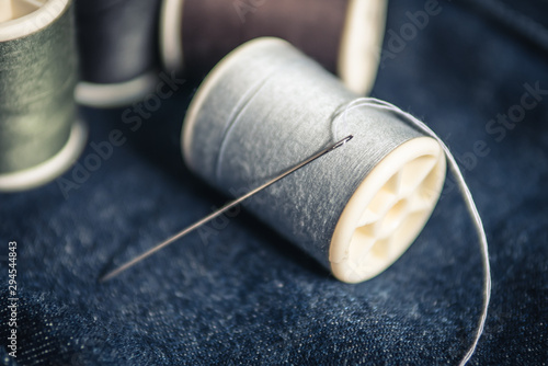 Needle and spool of thread on jeans fabric