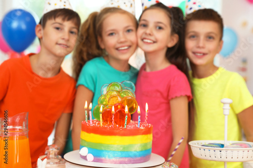 Children near cake with candles at birthday party indoors