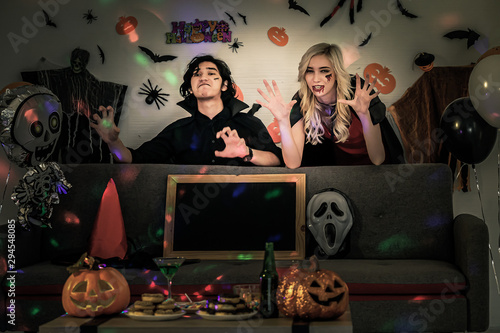 Beautiful woman dressed in dark-red dress and boyfriend to celebrate Halloween with scary makeup. Girl with a scary looking at a Halloween party