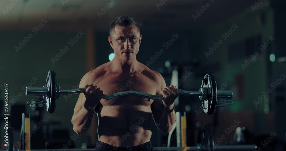Handsome man shakes arm muscles with barbell, basic exercises. Gym, bodybuilder doing exercises. Handsome man shakes arm muscles with barbell, basic exercises. Gym, bodybuilder doing exercises.