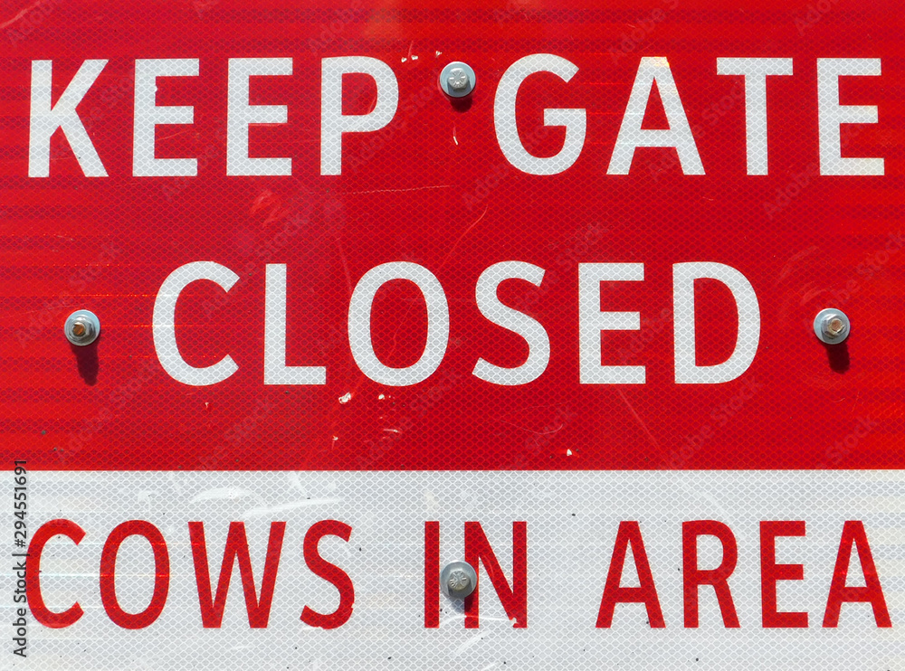 Red and white reflective sign, keep gate closed, cows in area