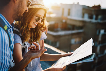 Multiethnic traveler couple using map together on sunny day