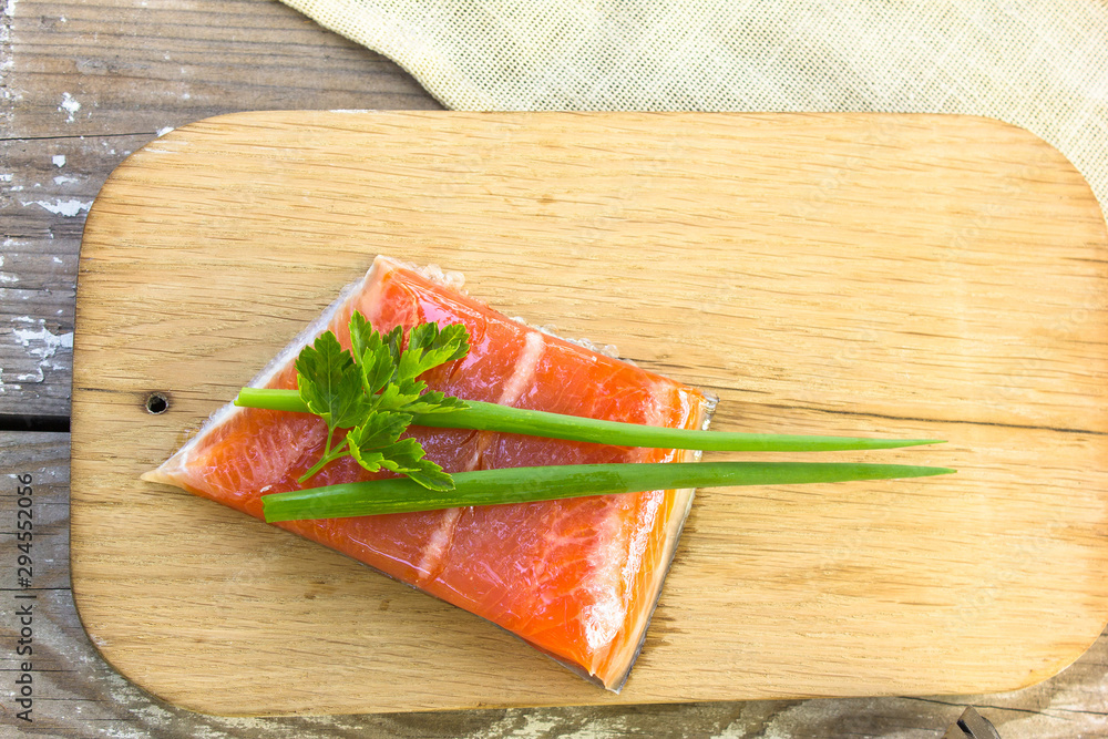 Fresh salted salmon fillet with parsley and onion on a wooden board. Concept of healthy food Fresh salted salmon fillet with parsley and onion on a wooden board. Concept of healthy food